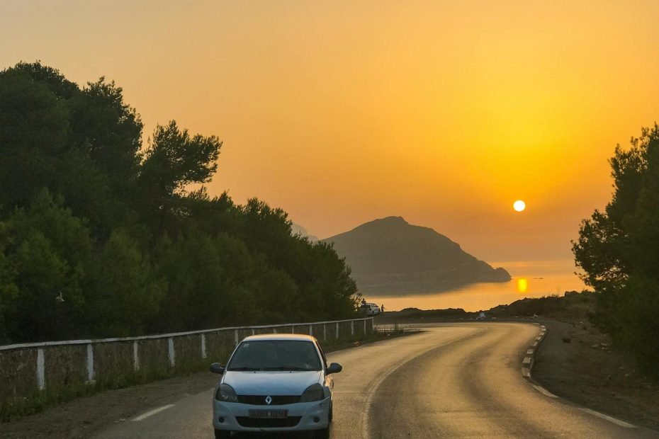 moving car on the road between green trees during sunset